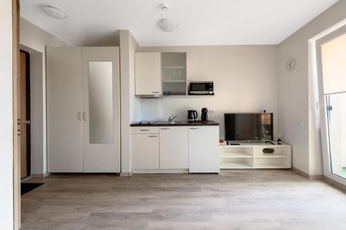 a white kitchen with white cabinets and a microwave at Cozy Mill apartment in Palanga