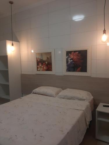 Un dormitorio con una cama con dos cuadros en la pared. en Aconchego e requinte flat Praia atalaia, en Aracaju