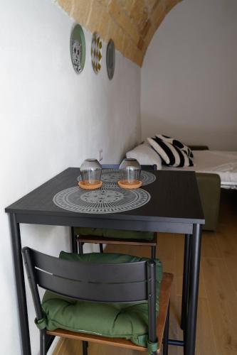 a small black table with two bowls on it with a bed at Sott'o Cambanil in Gioia del Colle