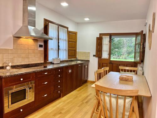 a kitchen with wooden cabinets and a wooden table with a wooden tableablish at Fuentes del Narcea apartamentos rurales in Cangas del Narcea