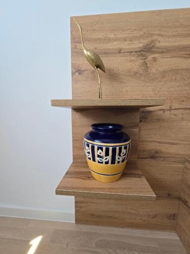 a vase on a wooden shelf with a plant in it at Jetsetters Corner Near Airport in Sarajevo