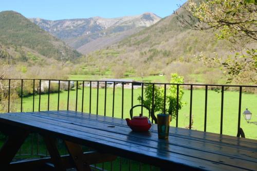 a picnic table with a tea pot on a balcony with mountains at Casa Rural Calzon Ordesa in Oto