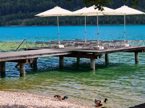 a pier with chairs and umbrellas on a lake at Haus im Park in Sankt Kanzian