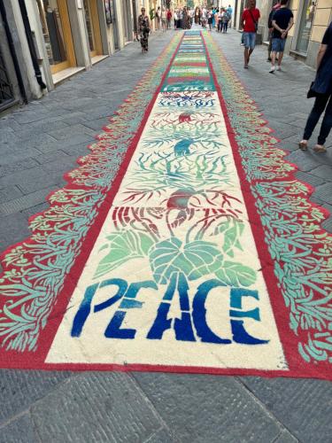 a rug with the word pain painted on it on a street at L'ARCO E' DI FIO in Camaiore