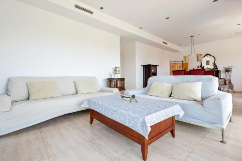 Una sala de estar con dos sofás blancos y una mesa. en Hauzify I Apartament Cala Pepo 2, en L'Ametlla de Mar