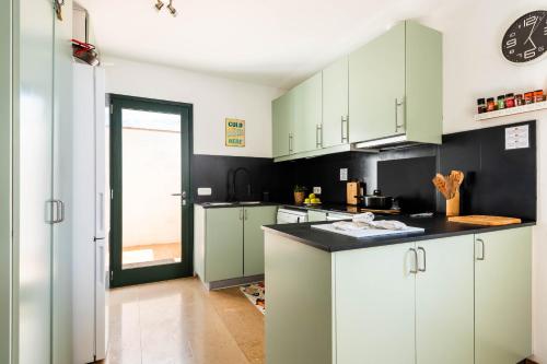 a kitchen with green cabinets and a black counter top at Vela Llatina - Binibeca Vell in Binibeca