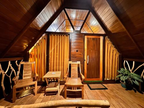 two chairs and a table in a room with wooden walls at The Mango Garden in Habarana