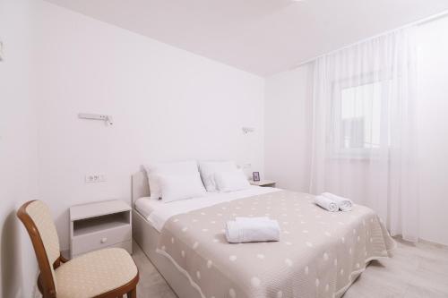 a white bedroom with a bed and a chair at Villa Mir Punta Radman in Petrcane