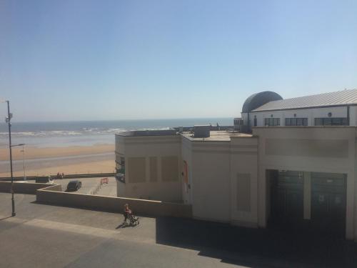 a person riding a bike next to a building with a beach at Spaview in Bridlington