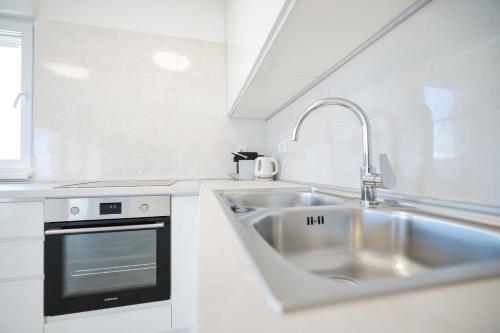 a white kitchen with a sink and a stove at Villa Mir Punta Radman in Petrcane