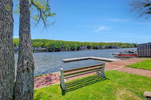 a bench sitting next to a lake with a dock at Lakefront home with kayaks fire pit hot tub and walk to restaurants and bars in Lake Harmony