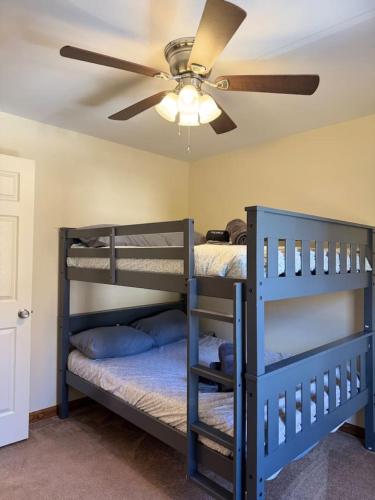 two bunk beds in a room with a ceiling fan at Lakefront home with kayaks fire pit hot tub and walk to restaurants and bars in Lake Harmony