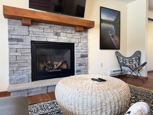 a living room with a stone fireplace with a tv at Lakefront home with kayaks fire pit hot tub and walk to restaurants and bars in Lake Harmony