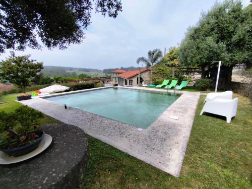 a swimming pool in a yard with chairs and a house at In Costa House - Alojamento Barcelos in Barcelos