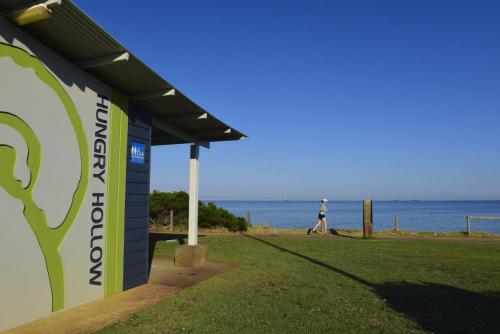 a person walking past a building near the ocean at Sandy Souls, Beach House in Bunbury