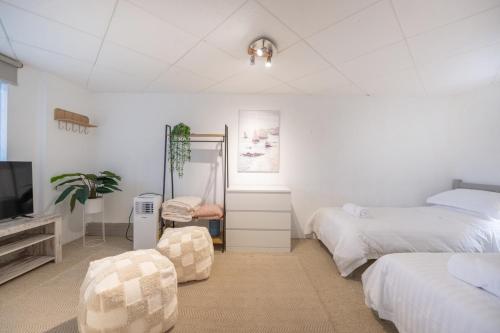 a white bedroom with two beds and a tv at Sandy Souls, Beach House in Bunbury