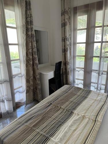 a bed in a bedroom with windows and a desk at Mami & Me Villa in Kendwa
