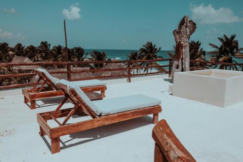a chair on the beach with the ocean in the background at Niken Beachfront Tulum Hotel in Tulum