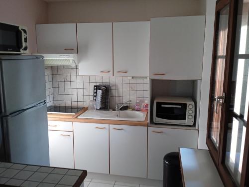 a kitchen with white cabinets and a sink and a microwave at Cours ruralité tranquillité in Cours