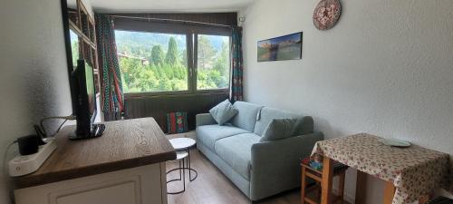 un salon avec un canapé bleu et une fenêtre dans l'établissement studio plein sud vue Mont Blanc CHAMONIX, à Chamonix-Mont-Blanc