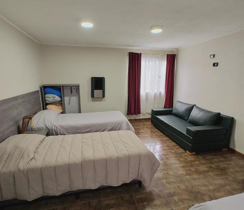 a hotel room with two beds and a couch at Alojamiento El Cóndor in Esquel