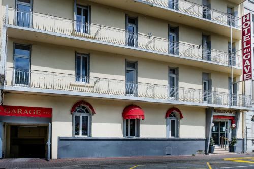 an apartment building with red awnings and windows at Hotel Du Gave in Lourdes