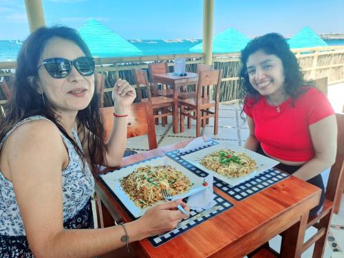 two women sitting at a table with two pizzas at H0TELIER Home, Máncora in Máncora