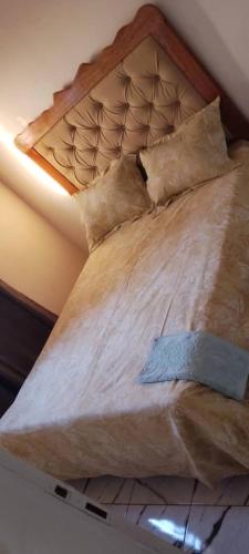 BafoussamにあるRésidence REHA, appart 2CHのベッド(木製のヘッドボード、枕付)