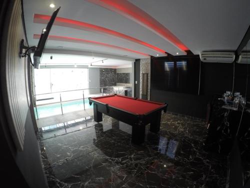 a red pool table in a room with a window at Motel Tenda in Maringá