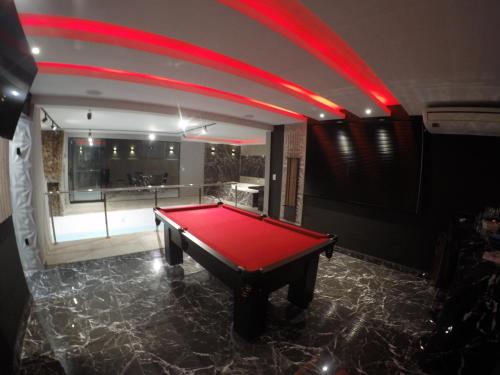 a pool table in a room with red lighting at Motel Tenda in Maringá