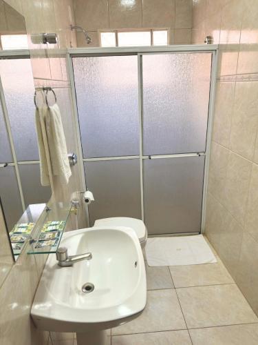 a bathroom with a sink and a shower with a toilet at Hotel Villa Rebellato in Olímpia