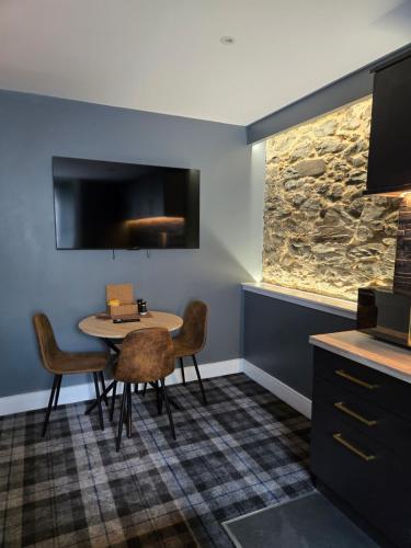 a dining room with a table and chairs and a tv at Lochview Apartment in Tarbet