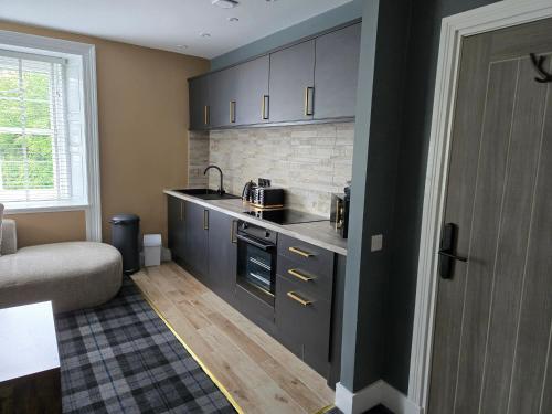 a kitchen with black cabinets and a couch in a room at Lochview Apartment in Tarbet