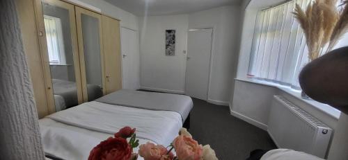 a small room with two beds and flowers in it at Lovely room like a home away home near the airport in Wythenshawe