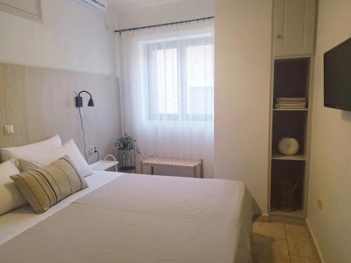 a bedroom with a white bed and a window at Selo Apartments Mani in Agios Nikolaos