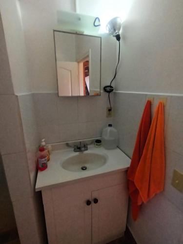 a bathroom with a sink and a mirror and orange towels at Blue haus in Punta Caribe