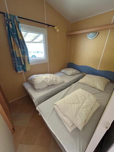Dos camas en una habitación pequeña con ventana. en La Cigale, en Le Grau d'Agde