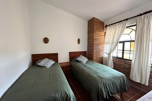 two beds in a room with a window at Comfort y Diseño cerca del Pueblo - 3 Recamaras in Mazamitla