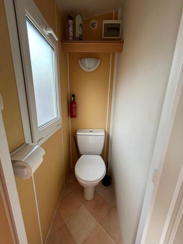Un pequeño baño con inodoro y ventana. en La Cigale, en Le Grau d'Agde