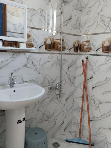 a bathroom with a sink and a white marble wall at Belle maison près de la plage in Chefchaouene