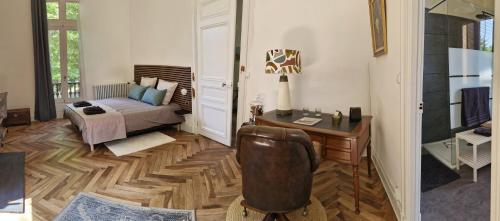 a bedroom with a bed and a desk and a chair at Le Manoir de la Belle Endormie in Valréas