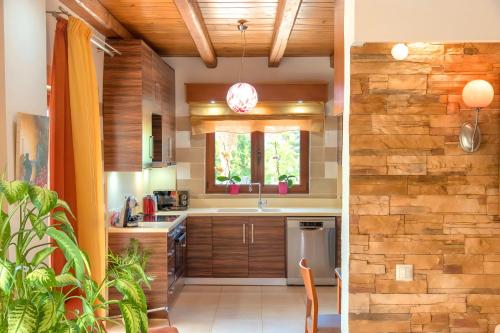 a kitchen with wooden cabinets and a brick wall at Cretan Dream Villa in Georgioupolis