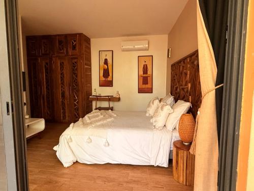 a bedroom with a bed with white sheets at Villa YEMAYA - Suite bungalow indépendant in Ngaparou
