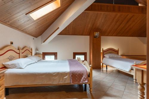 two beds in a bedroom with wooden ceilings at Hotel & Restaurant AL TRIVIO in Altana
