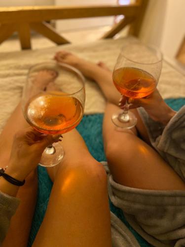 two women sitting on a bed holding wine glasses at Cabernet Cabaña - La Cava Lodge in Medellín