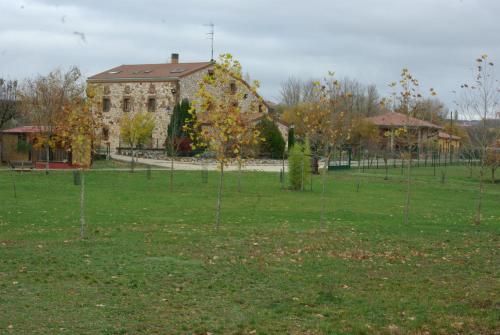 a building in a field with trees in front of it at Bungalows Granja Escuela Arlanzón in Arlanzón