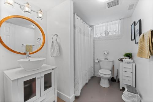 a white bathroom with a sink and a mirror at Family-friendly 2br Near Lake & Downtown in Cobourg