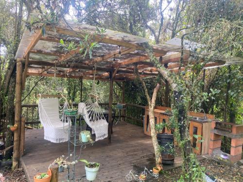 a wooden pergola with a table and chairs on a deck at Cabernet Cabaña - La Cava Lodge in Medellín