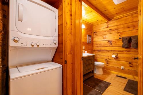 een witte wasmachine en droger in een houten badkamer bij Quiet Way Cabin By Avada Properties in Sevierville