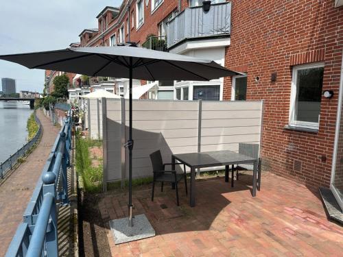a table and chairs under an umbrella on a patio at Terrassenwohnung City an der Kleinen Weser in Bremen